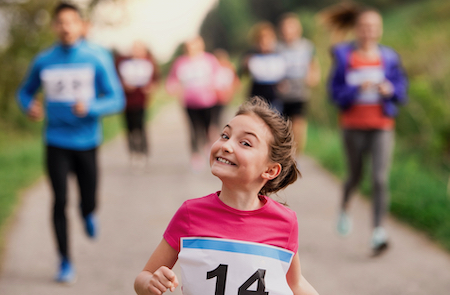 A large group of active multi generation people running a race competition in nature.